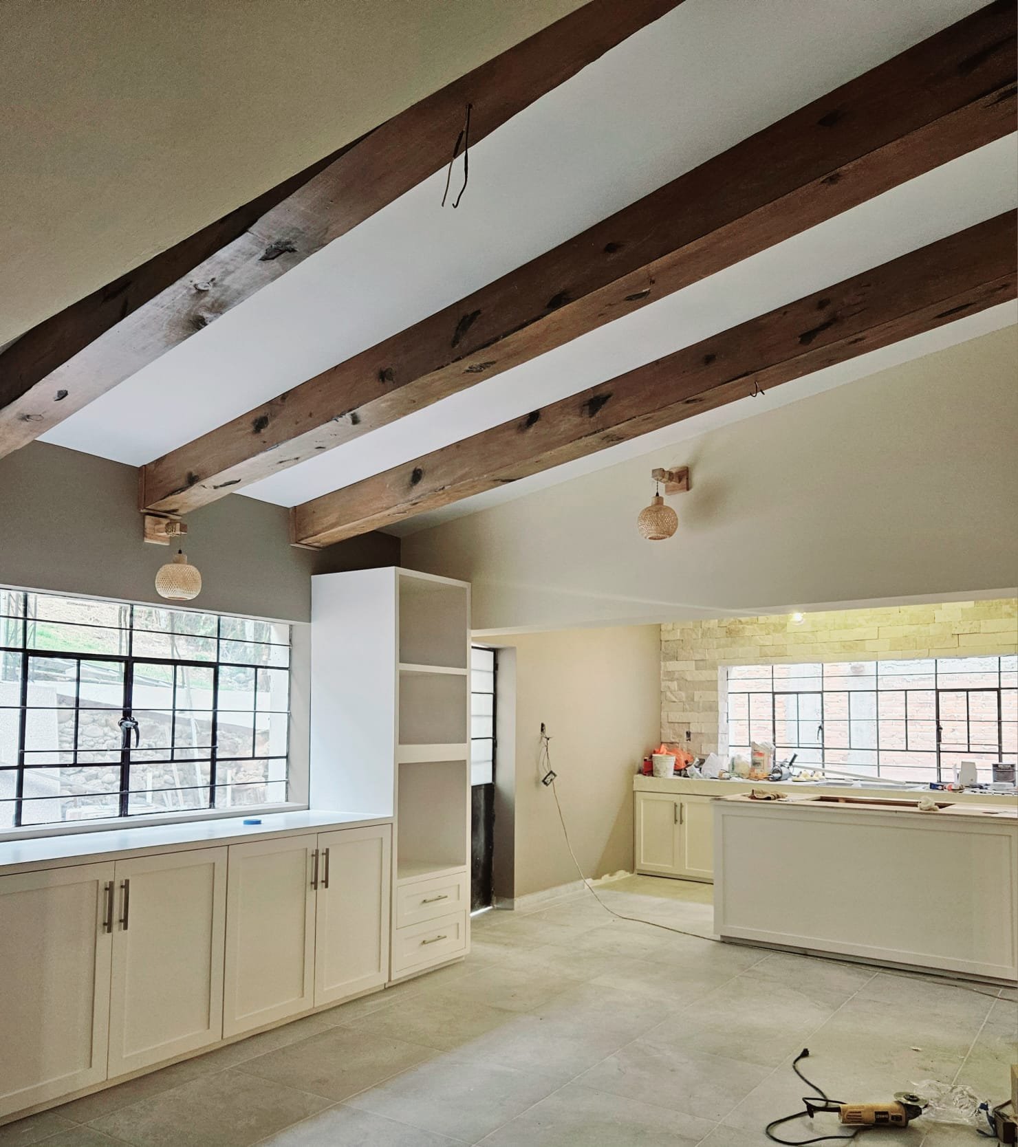 "Sala elegante con travesaños de madera en el techo, combinando diseño moderno y calidez para una remodelación sofisticada."