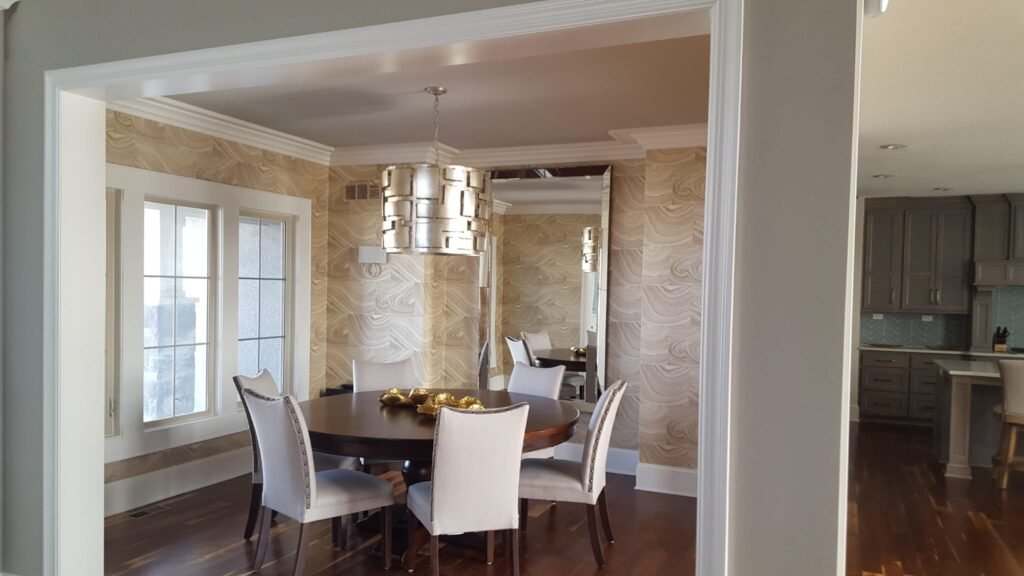 "Comedor elegante con paredes de acabado artístico en madera, techo y muros blancos, y un ventanal que aporta luz natural y amplitud al espacio."